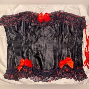 simple yet sexy black corset with red and black lace detailing and red bows.